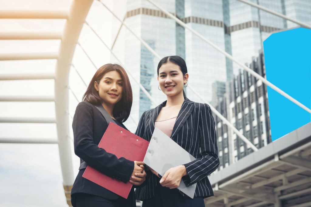 Two business woman standing and discussing in front of the office. Business working concept.